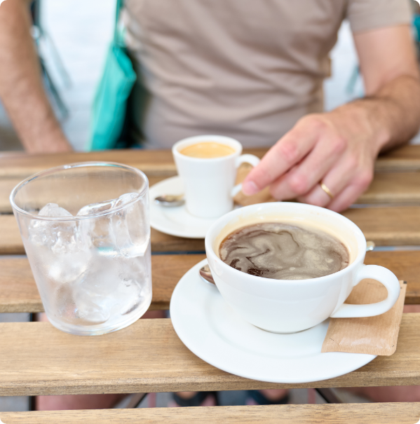 Reusable glass and ceramic cups on a café table, representing affordable plastic-free alternatives.