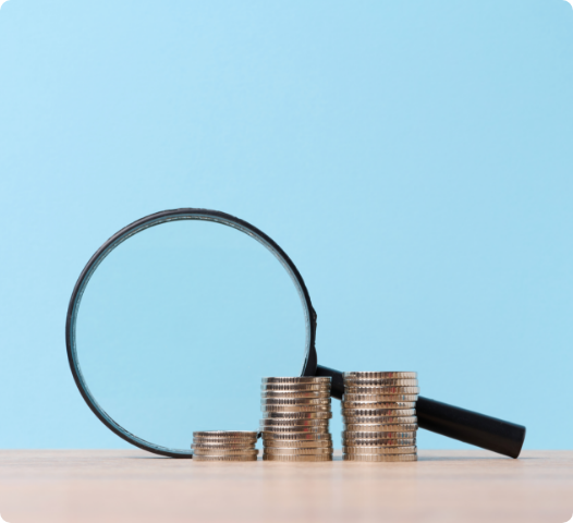 Magnifying glass over stacked coins, representing economic costs and benefits of reducing plastic.