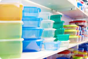 Stacked plastic food storage containers in various sizes and colors on retail shelves.
